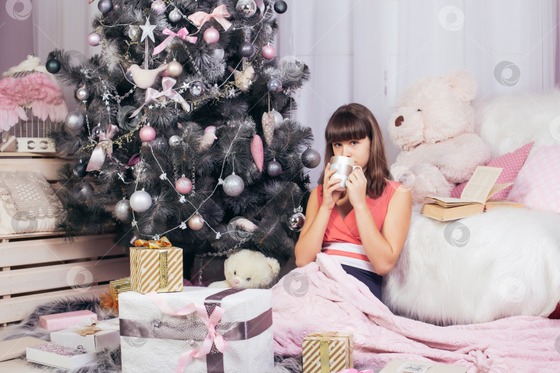 Скачать Девочка-подросток пьет чай в новогодней гостиной фотосток Ozero