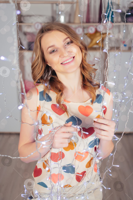 Скачать Молодая красивая мечтательная женщина с гирляндами улыбается в День Святого Валентина фотосток Ozero
