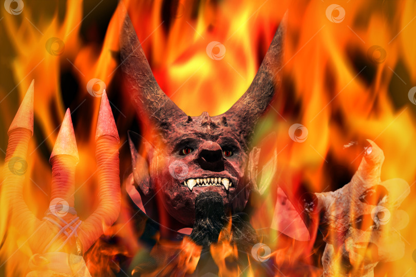 Скачать Дьявол в огне на темном фоне. Человек в страшной маске дьявола, Хэллоуин. фотосток Ozero
