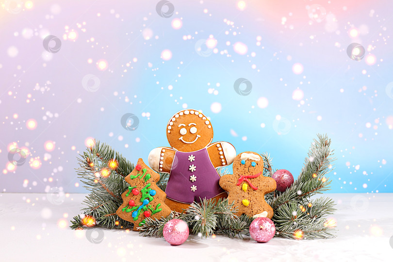 Скачать с Новым Годом. Праздничная зимняя поздравительная открытка, пряники и рождественские украшения на заснеженных еловых ветках, концепция Сочельника, новогодний фон с огнями и украшениями фотосток Ozero