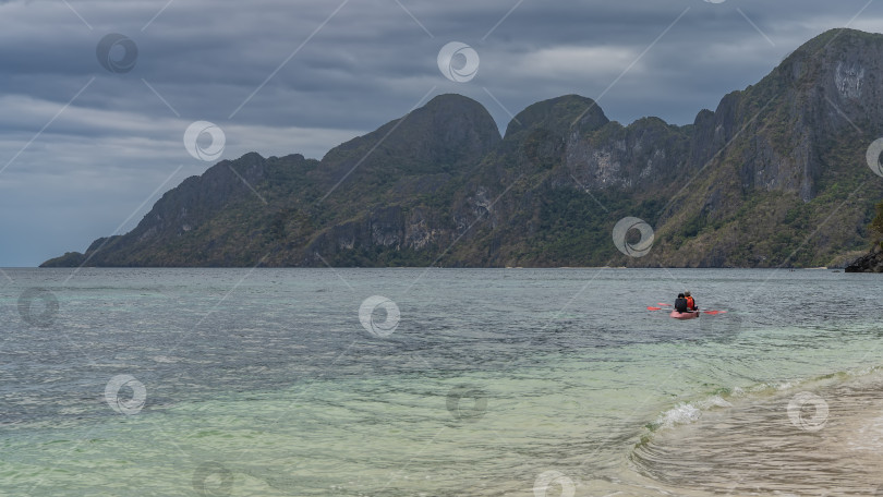 Скачать Туристическое каноэ плывет по бирюзовому океану. Весла над водой фотосток Ozero
