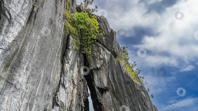 Скачать Отвесный карстовый утес на фоне голубого неба и облаков. фотосток Ozero