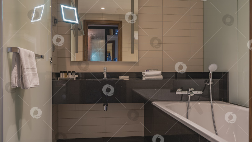 Скачать Интерьер ванной комнаты. Белая прямоугольная ванна, металлический смеситель, душевая кабина. фотосток Ozero