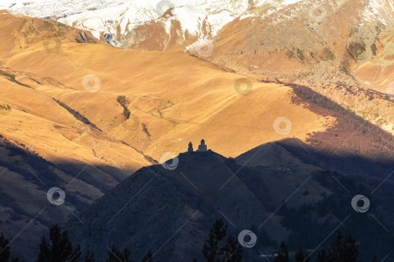 Скачать Церковь Гергети, Грузия, золотистого цвета на закате. Вид издалека. фотосток Ozero