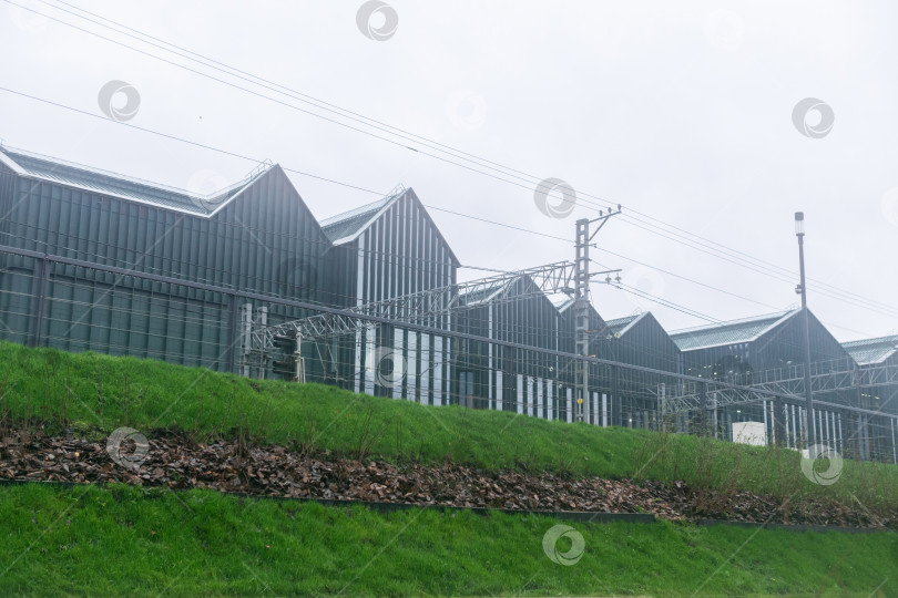 Скачать Затуманенный вид на современное промышленное здание за железнодорожными путями фотосток Ozero