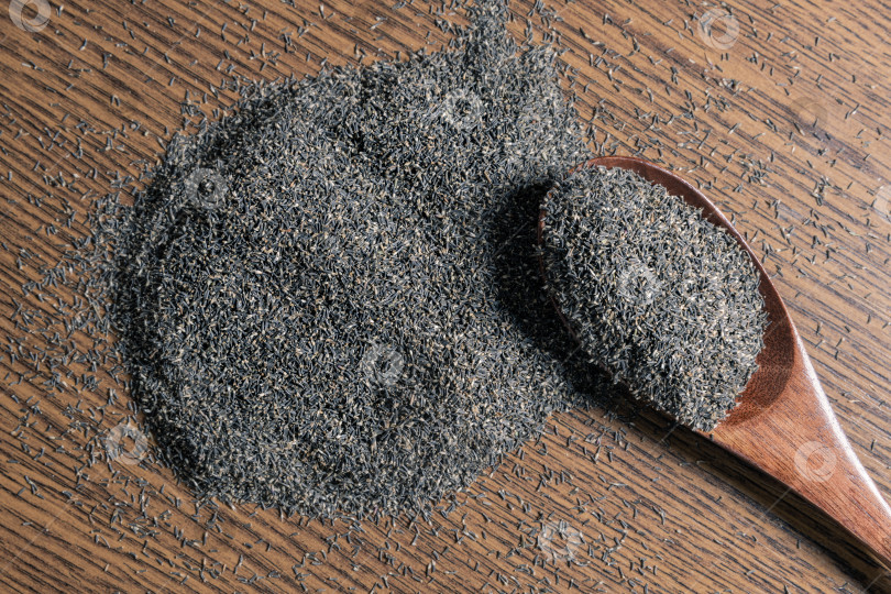 Скачать Семена цветков агератума высыпьте на деревянный стол и положите в деревянную ложку. фотосток Ozero