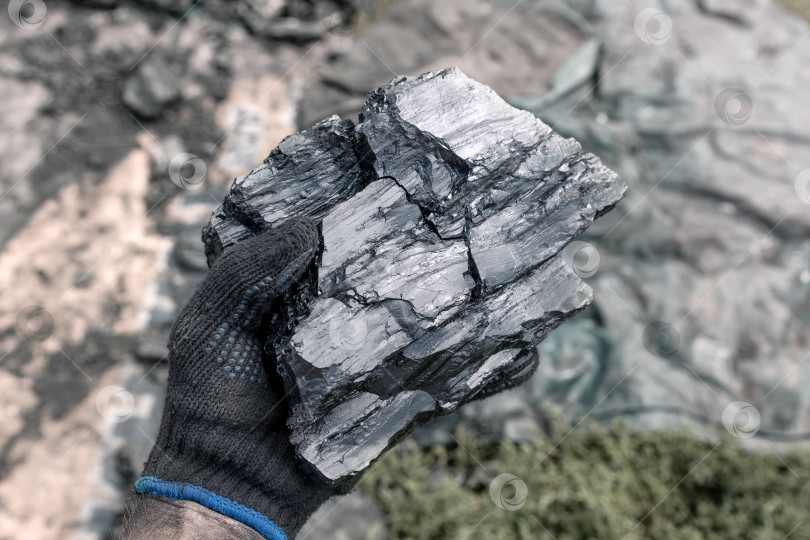 Скачать Кусок угля в руке мужчины на размытом фоне.  фотосток Ozero