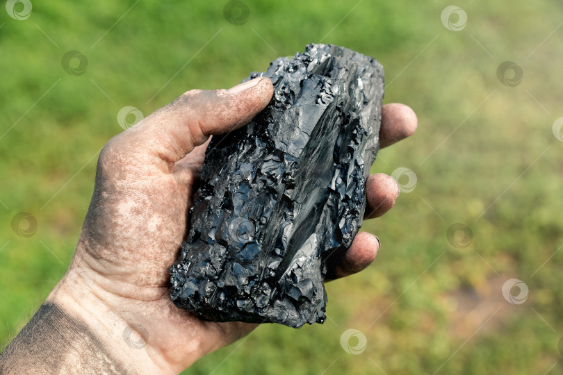 Скачать Кусок угля в грязной руке шахтера. Энергетика и топливная промышленность. фотосток Ozero