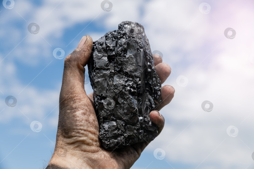 Скачать Кусок угля в руке, поднятой к небу. фотосток Ozero