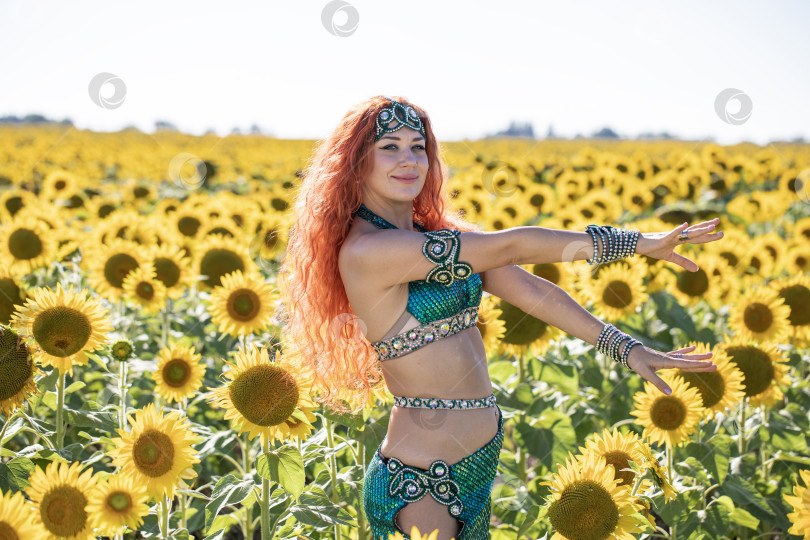 Скачать Рыжеволосая восточная танцовщица позирует на поле подсолнухов. фотосток Ozero
