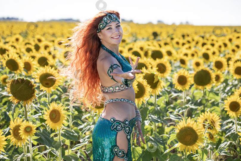 Скачать Рыжеволосая восточная танцовщица позирует на поле подсолнухов. фотосток Ozero