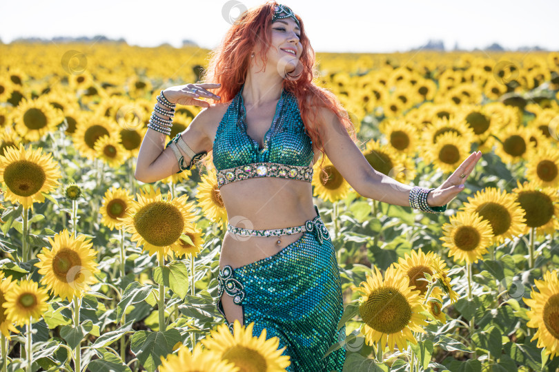 Скачать Рыжеволосая восточная танцовщица позирует на поле подсолнухов. фотосток Ozero