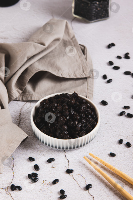 Скачать Азиатская ферментированная черная фасоль на тарелке на столе, вид сверху фотосток Ozero