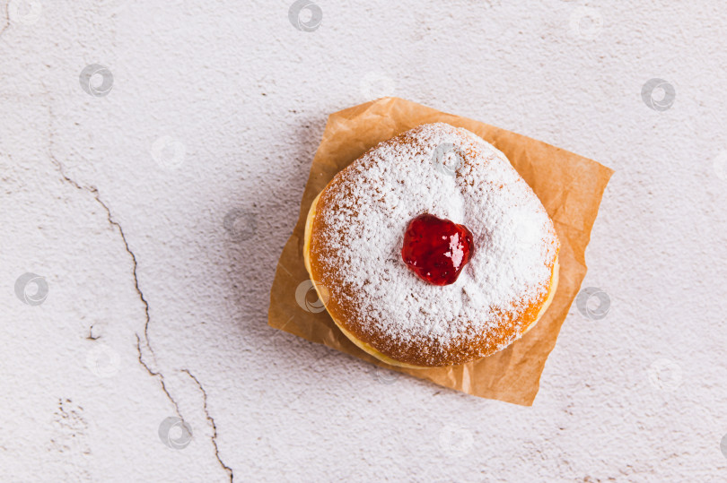 Скачать Вкусные пончики с джемом в сахарной пудре на пергаментной бумаге на столе вид сверху фотосток Ozero