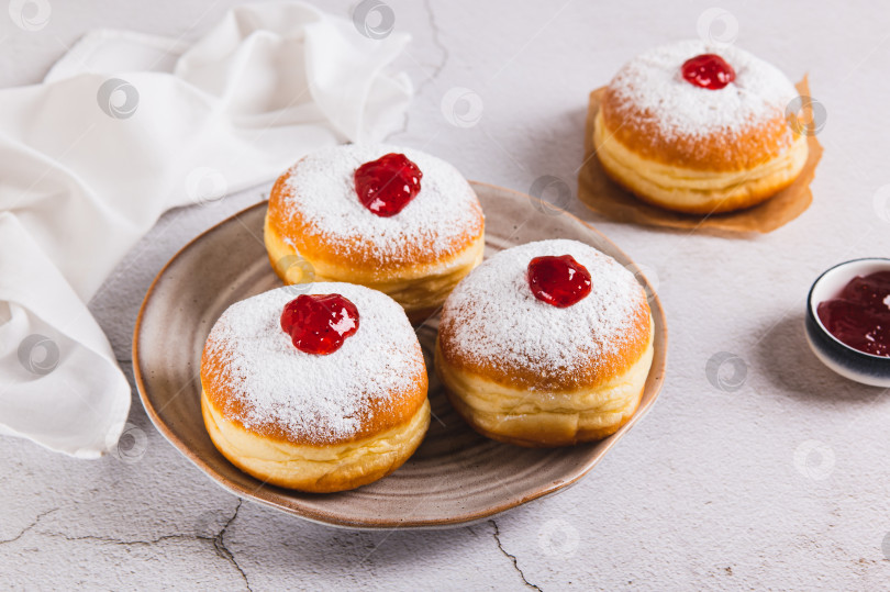 Скачать Вкусные пончики с начинкой из джема и сахарной пудрой на тарелке на столе фотосток Ozero