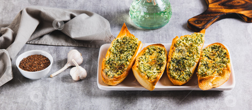 Скачать Запеченный багет со сливочным маслом, чесноком и укропом на тарелке на столе веб-баннер фотосток Ozero