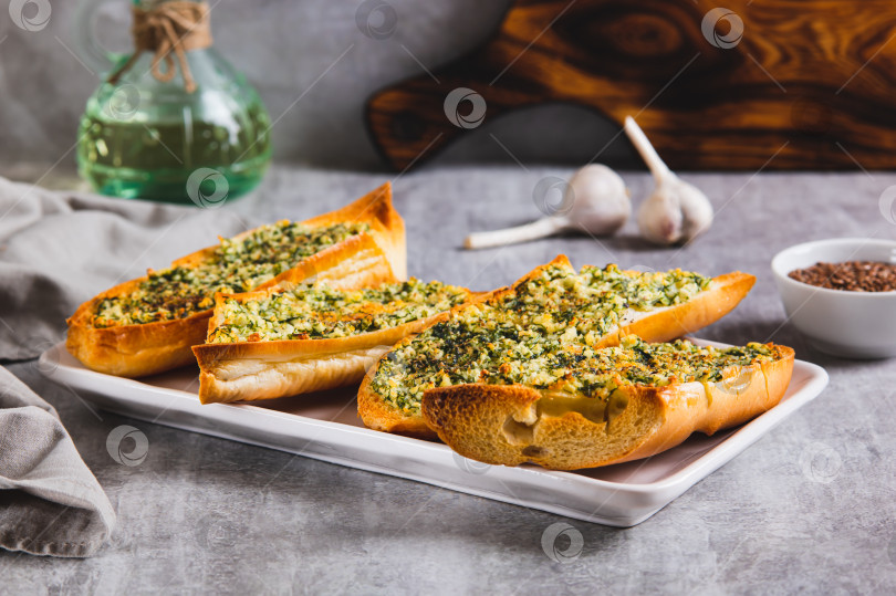 Скачать Запеченный багет со сливочным маслом, чесноком и укропом на тарелке на столе фотосток Ozero