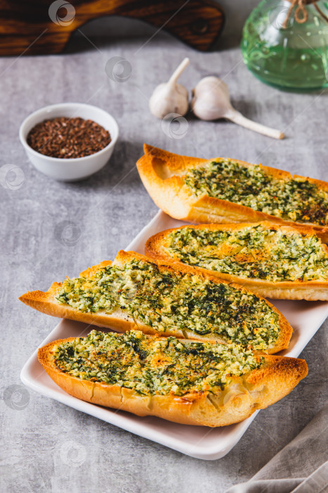 Скачать Золотистый чесночный хлеб с зеленью на тарелке на столе, вид сверху фотосток Ozero