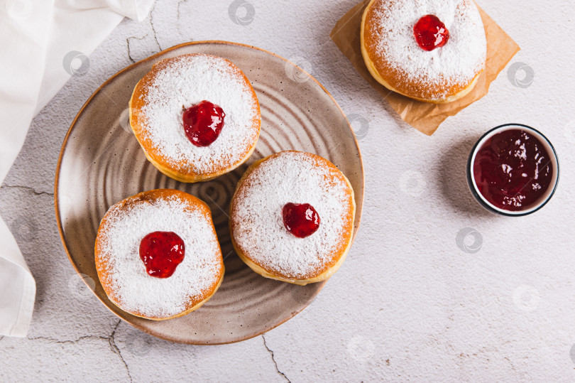 Скачать Сладкие пончики в сахарной пудре с джемом на тарелке на столе вид сверху фотосток Ozero