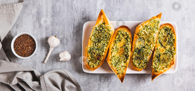 Скачать Золотистый чесночный хлеб с зеленью на тарелке на столешнице посмотреть веб-баннер фотосток Ozero