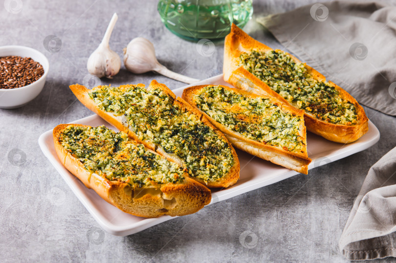 Скачать Золотистый чесночный хлеб с зеленью на тарелке на столе фотосток Ozero