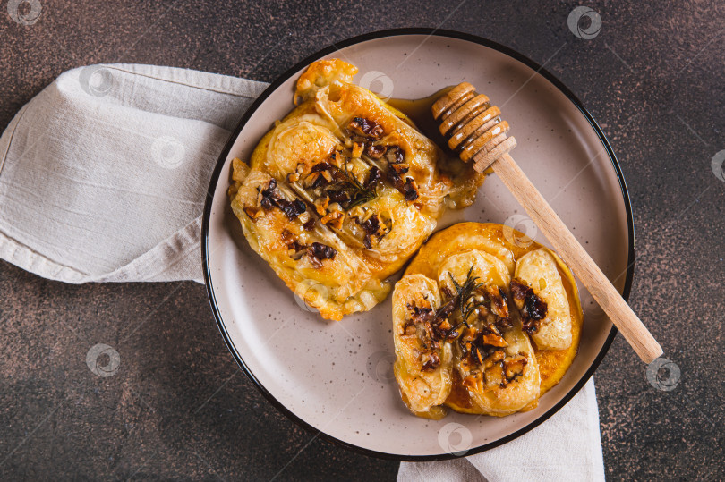 Скачать Запеченная тыква крупным планом с сыром бри, орехами, розмарином и медом на тарелке, вид сверху фотосток Ozero