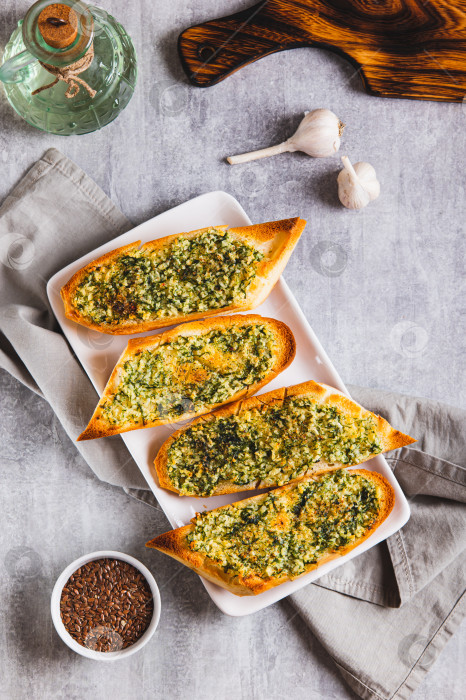 Скачать Золотистый чесночный хлеб с зеленью на тарелке, установленной на столешнице вертикально фотосток Ozero