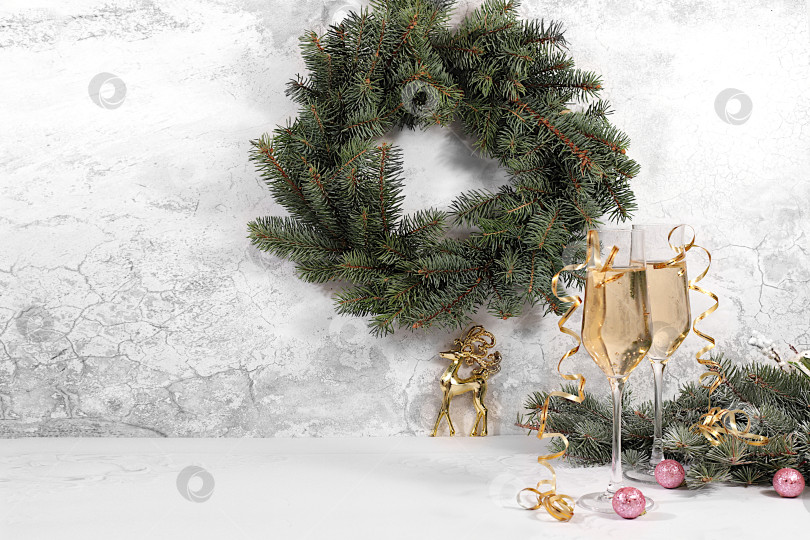 Скачать с Новым Годом. Два бокала шампанского на праздничном фоне еловых веток и украшений - концепция кануна Рождества. Рождественский и новогодний макет для дизайна и продаж продукции фотосток Ozero