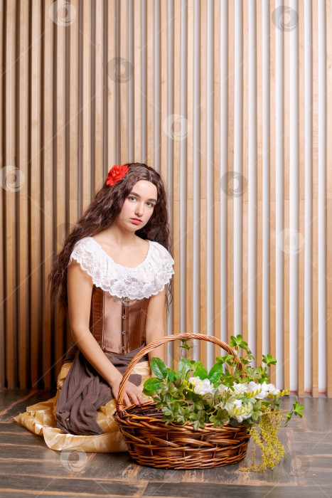 Скачать Женщина в белом платье сидит на полу, держа в руках корзину с цветами фотосток Ozero