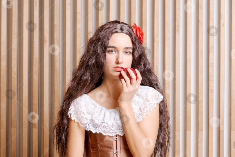 Скачать Женщина с длинными каштановыми волосами держит в руке яблоко фотосток Ozero