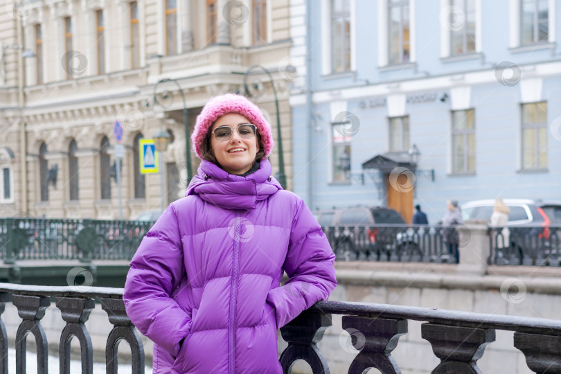 Скачать Женщина в фиолетовом пальто и розовой шляпе стоит на мосту фотосток Ozero