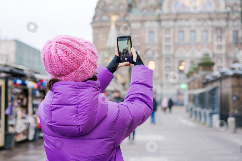 Скачать Женщина в розовой шляпке фотографирует здание на мобильный телефон фотосток Ozero