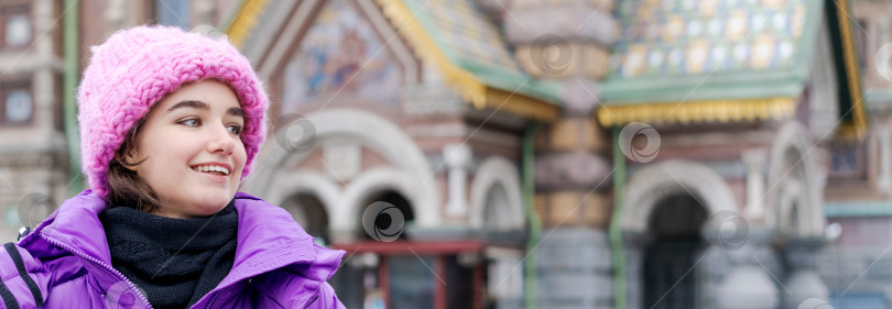 Скачать Женщина в розовой шляпке и фиолетовом пальто улыбается перед зданием фотосток Ozero