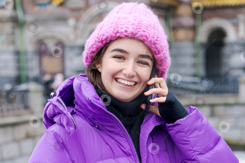 Скачать Женщина в фиолетовом пальто и розовой шляпе разговаривает по мобильному телефону фотосток Ozero