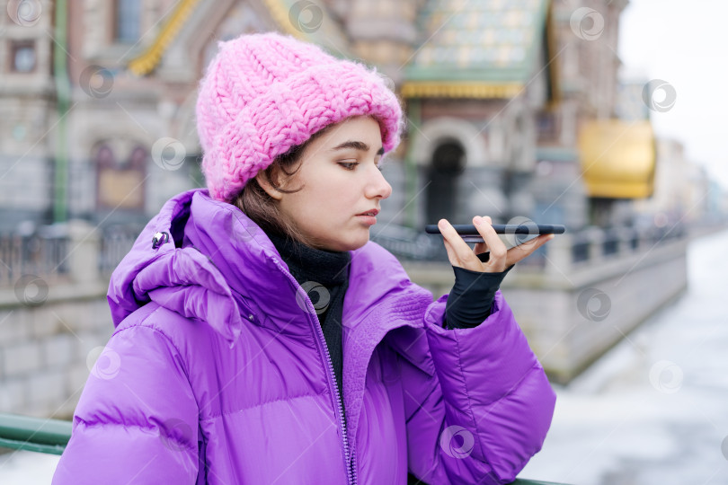 Скачать Женщина в розовой шляпке и фиолетовом пальто разговаривает по мобильному телефону фотосток Ozero