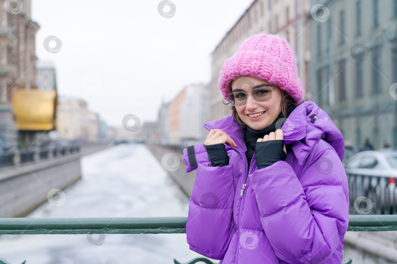 Скачать Женщина в фиолетовом пальто и розовой шляпе стоит на мосту фотосток Ozero