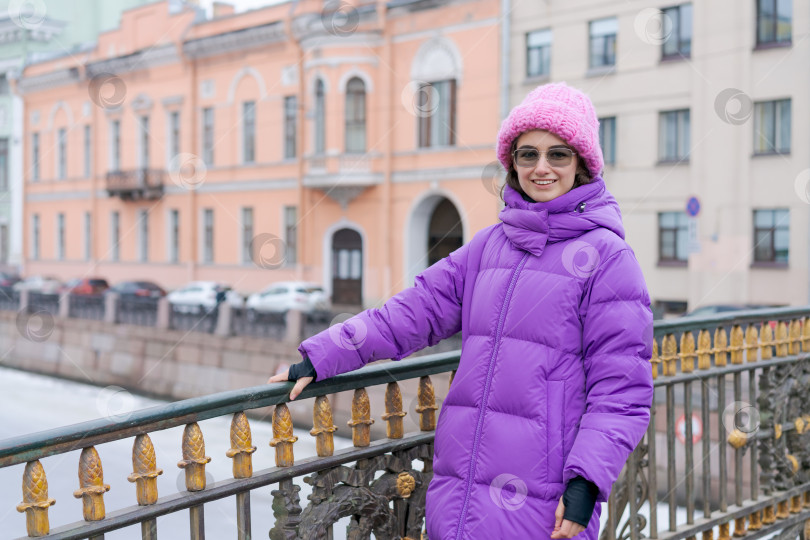 Скачать Женщина в фиолетовом пальто и розовой шляпе стоит на мосту фотосток Ozero