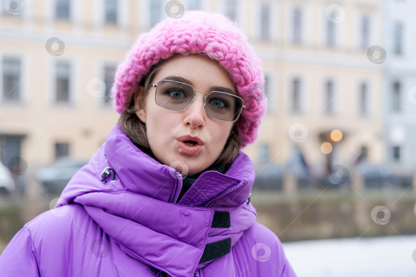 Скачать Женщина в розовой шляпке и фиолетовом пальто стоит перед зданием фотосток Ozero