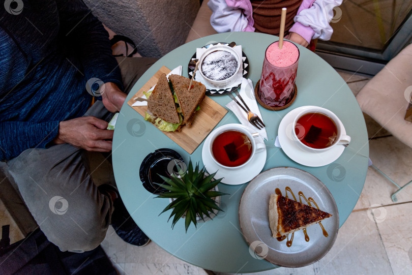 Скачать Вид сверху на чайный столик, молочный коктейль, брауни и чизкейк, кофейня для завтрака фотосток Ozero