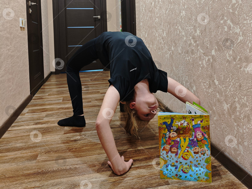 Скачать Все успеть. Девочка читает журнал и тренируется  стоять на мостике. Девушка читает журнал и тренируется стоять на мосту. фотосток Ozero