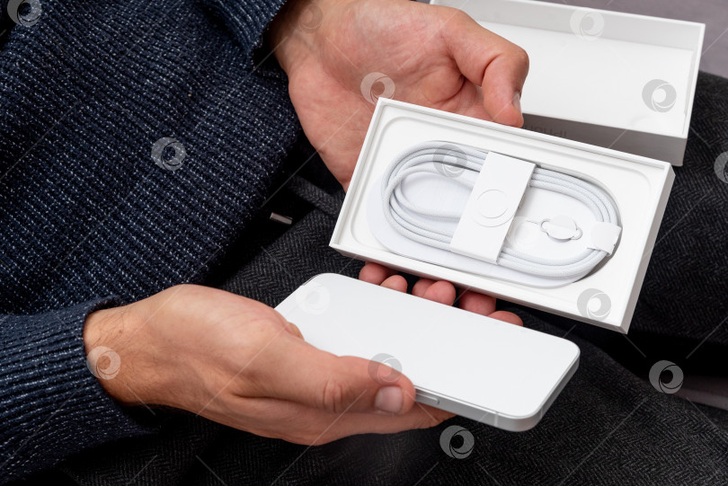 Скачать Бар, Черногория, 2 ноября 2025 года, Мужчина распаковывает новый смартфон iphone в открытой коробке фотосток Ozero