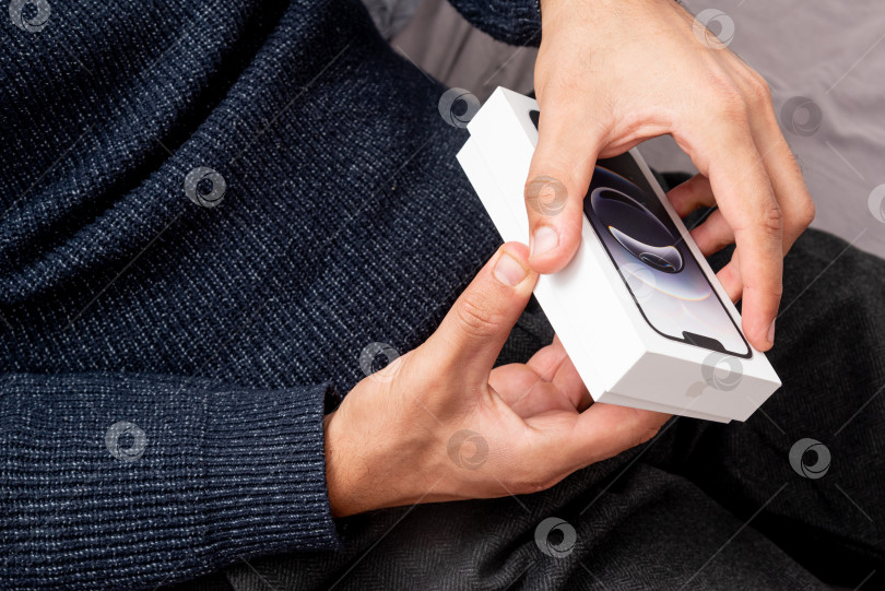 Скачать Бар, Черногория, 2 ноября 2025 года, Мужчина распаковывает новый смартфон iphone в открытой коробке фотосток Ozero