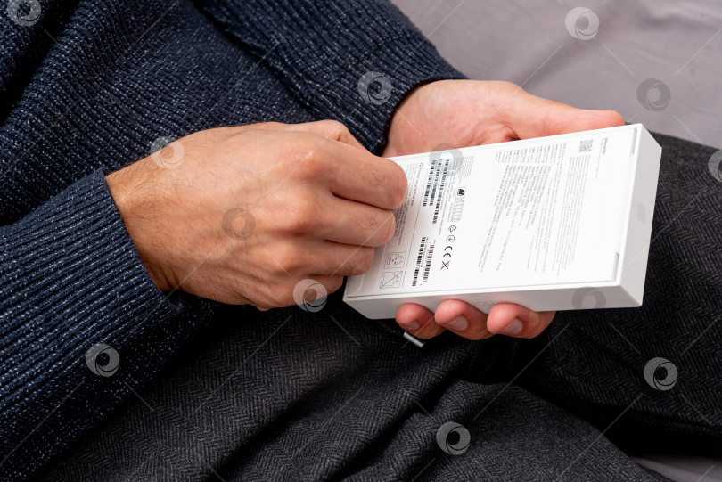 Скачать Бар, Черногория, 2 ноября 2025 года, Мужчина распаковывает новый смартфон iphone в открытой коробке фотосток Ozero