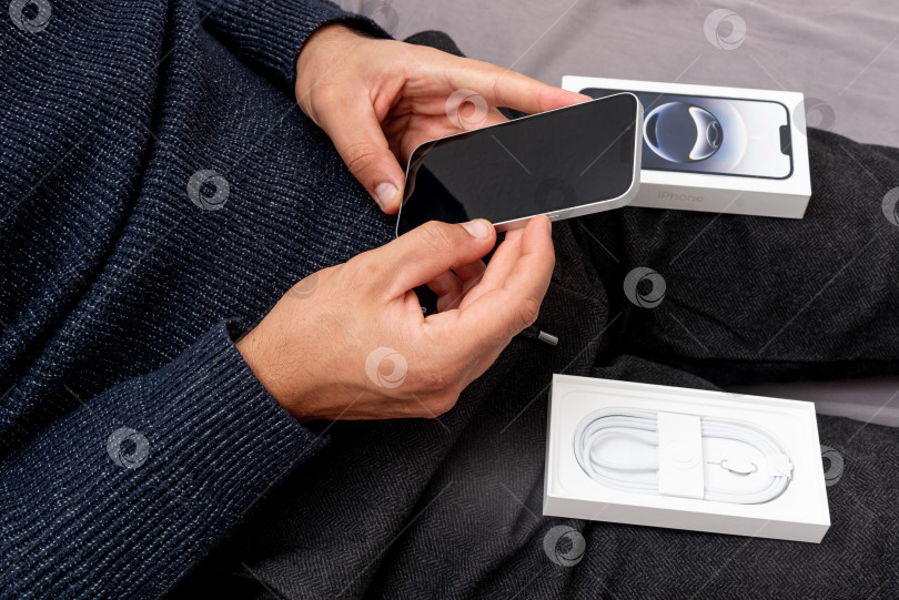 Скачать Бар, Черногория, 2 ноября 2025 года, Мужчина распаковывает новый смартфон iphone в открытой коробке фотосток Ozero