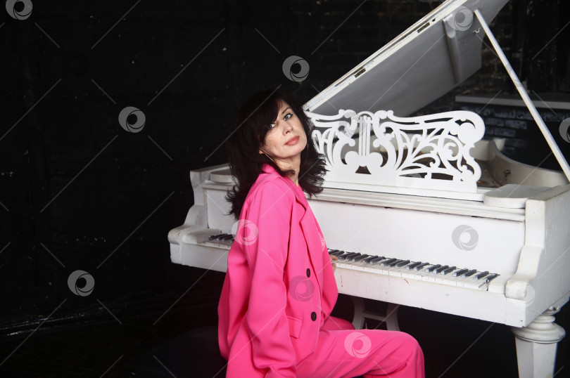 Скачать Красивая девушка у пианино в розовом наряде фотосток Ozero