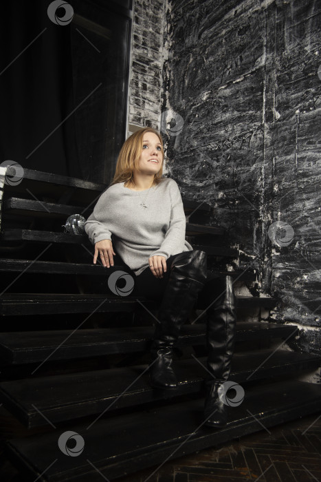 Скачать Молодая девушка в серой кофте позирует на лестнице фотосток Ozero