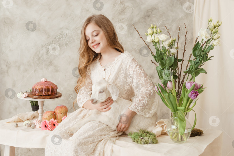 Скачать Девушка сидит за пасхальным столом с куличами, весенними цветами и перепелиными яйцами и держит на руках беленького малыша. Счастливого празднования Пасхи фотосток Ozero
