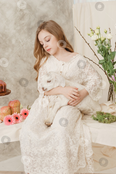 Скачать Девушка сидит за пасхальным столом с куличами, весенними цветами и перепелиными яйцами и держит на руках беленького малыша. Счастливого празднования Пасхи фотосток Ozero