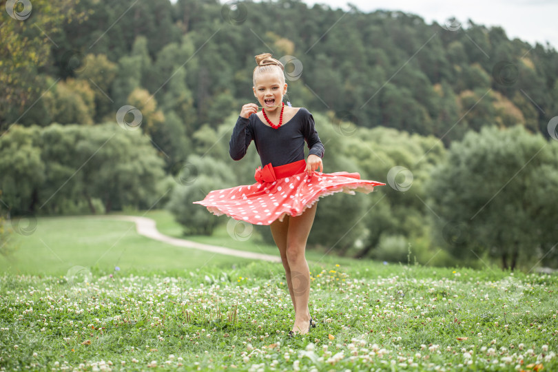 Скачать Маленькая девочка танцует ретро-танец в стиле пин-ап в летнем парке фотосток Ozero