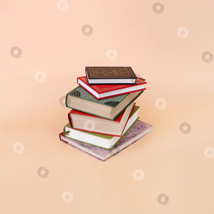 Скачать Стопка книг в цветных обложках с белыми листами, выделяющимися на розовом фоне фотосток Ozero